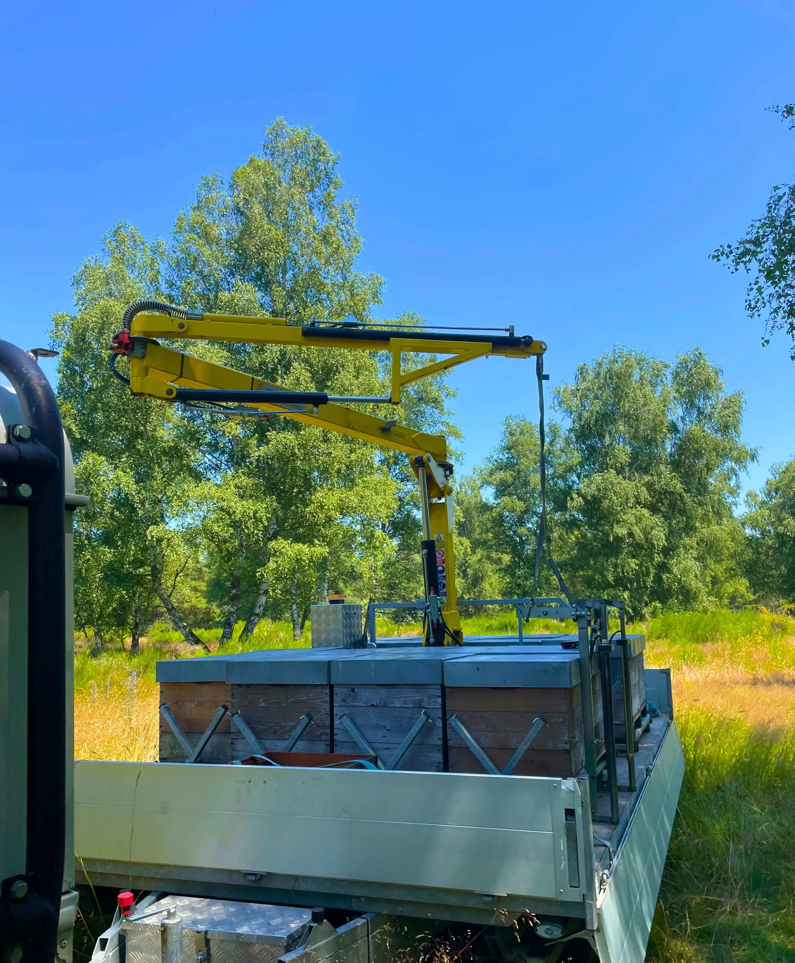 Bienenbeuten stehen auf Anhänger Bienenbeuten auf Anhänger mit Kran an einem sonnigen Tag